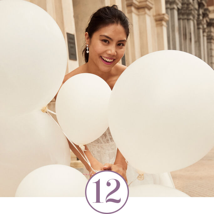 bride holding a bunch of balloons in front of her