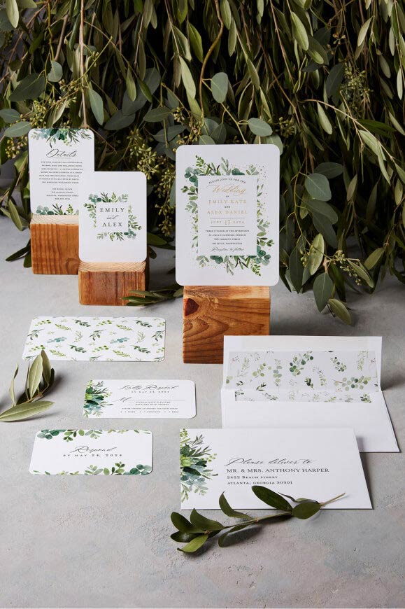 wedding invitations displayed on wood blocks next to vines on a table