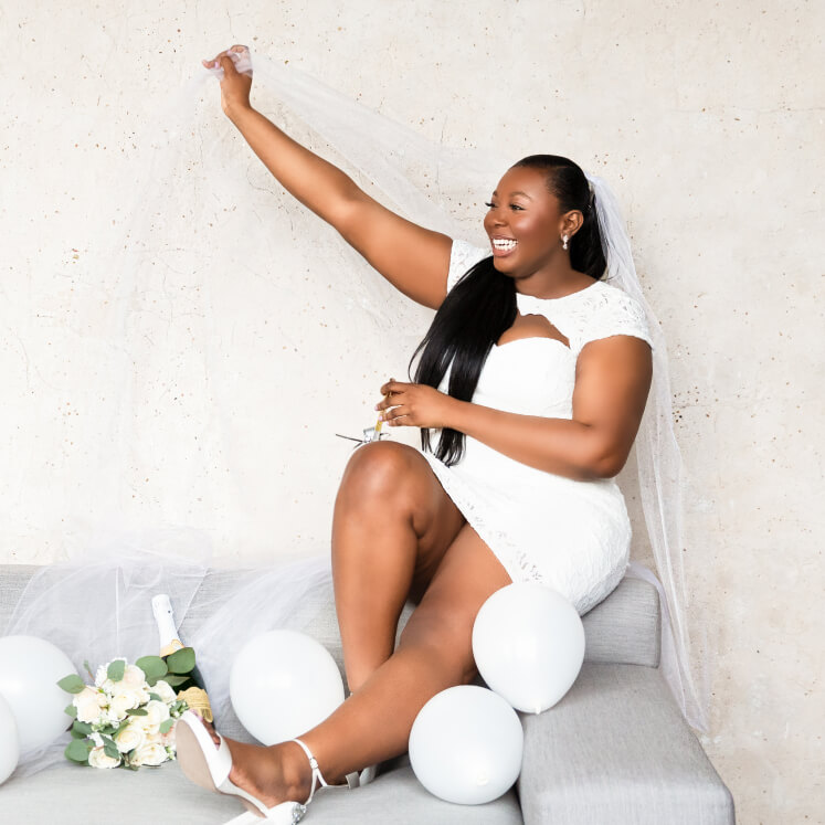 bride in wedding dress sitting on a couch with champagne