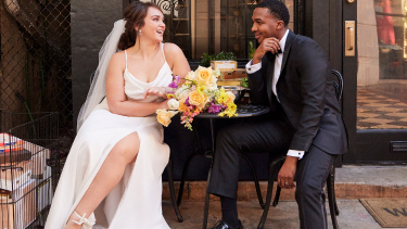 bride and groom sitting at a table outside of a building