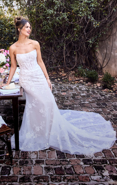 woman in wedding dress leaning against a table outside