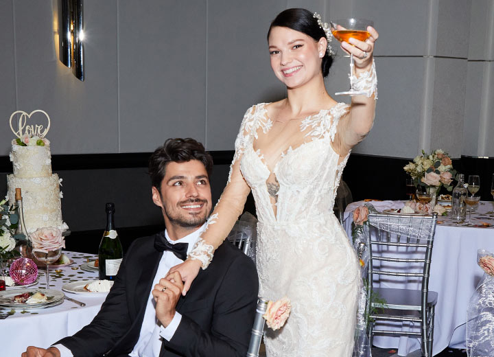 bride raising a glass for a toast while holding hands with a groom