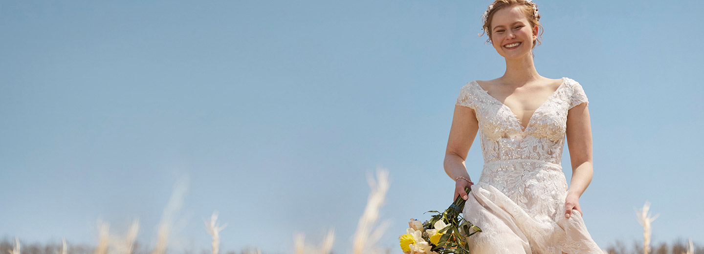 Bride in field smiling and holding a bouquet
