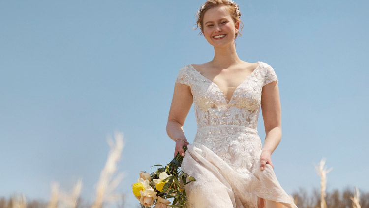 Bride in field smiling and holding a bouquet
