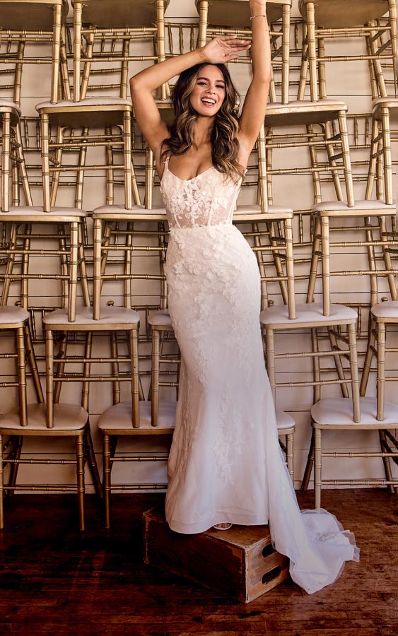 woman in wedding dress standing in front of stacks of chairs