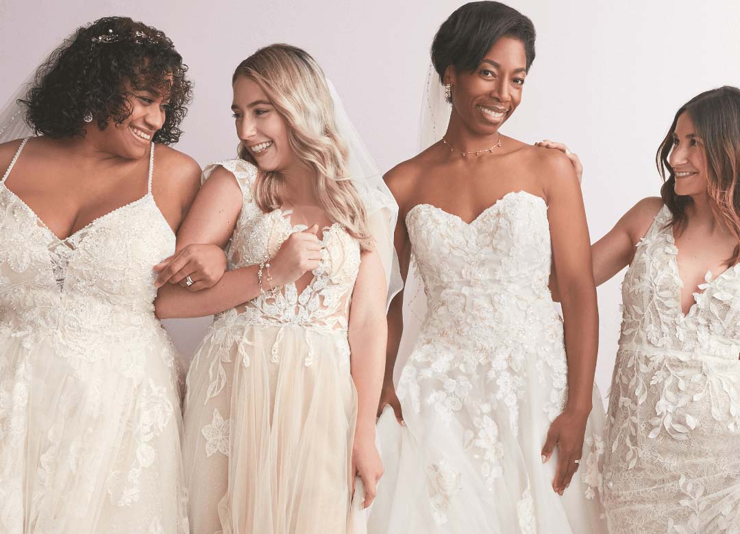 4 brides in wedding dresses laughing and smiling