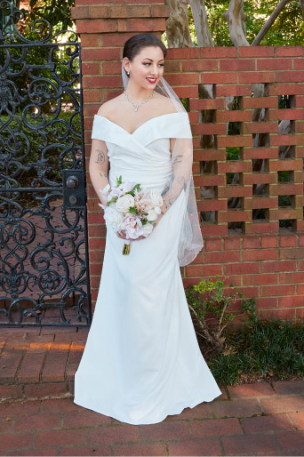 bride holding bouquet and standing in front of gate