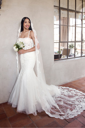 woman in wedding dress holding bouquetand standing in front of a wall