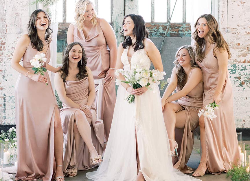 bride holding flower bouquet standing with bridesmaids wearing pink dresses