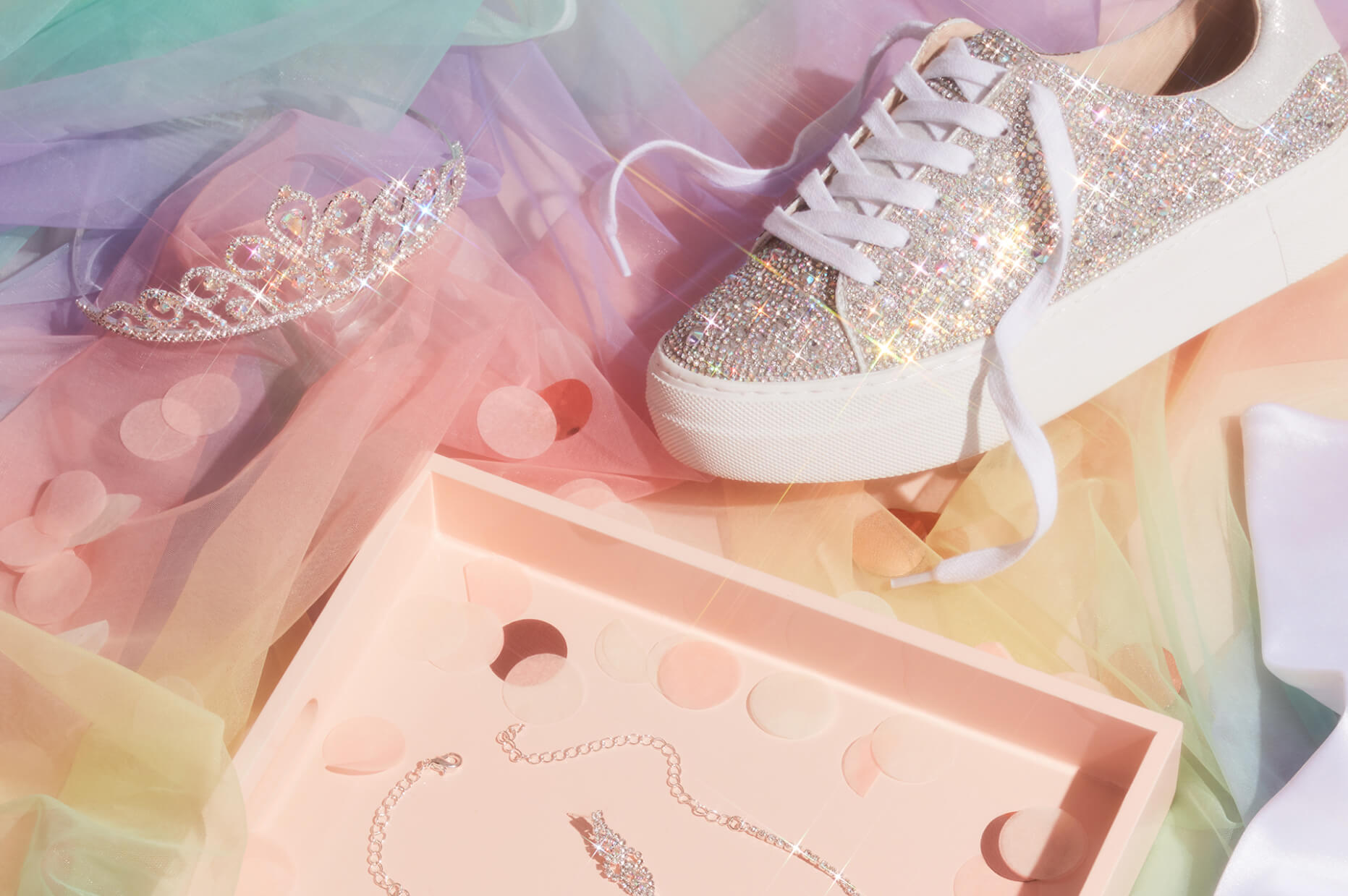 sparkly sneakers, tiara, and jewelry box laid out on top of multi colored tulle