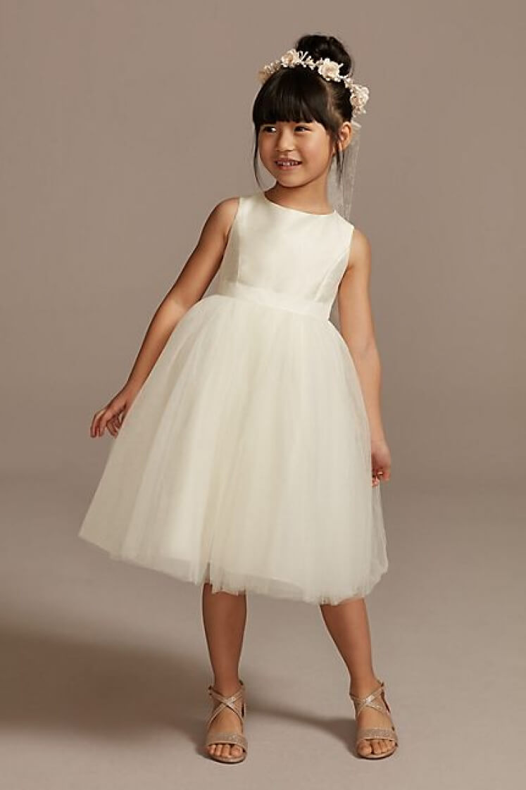 flower girl in a sleeveless dress and wearing a headband leaning to one side