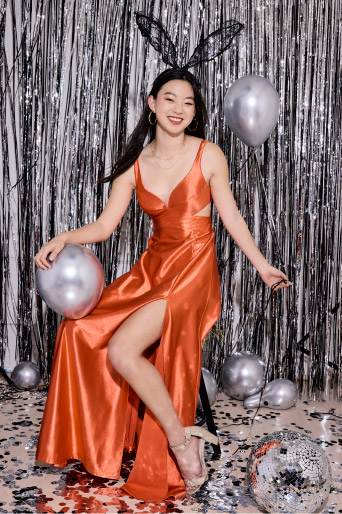 girl in orange prom dress and bunny ears holding silver balloons