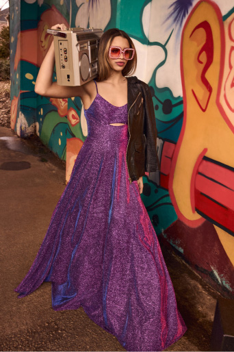 girl in purple prom dress holding a boombox and walking next to a colorful mural