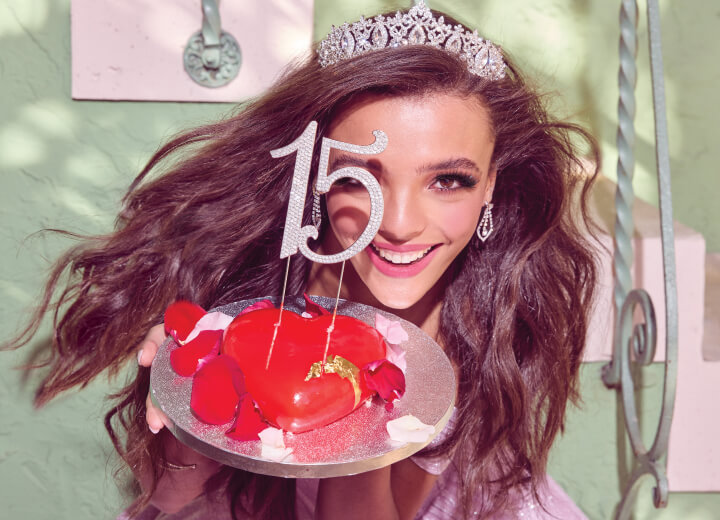 young woman wearing a veil and holding a cake with 15 on it
