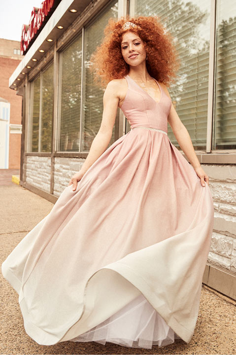 girl in flowy pink prom dress standing outside of a diner