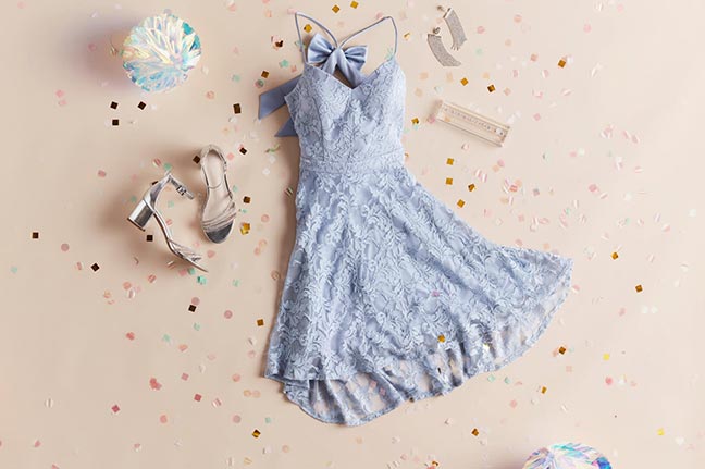 blue dress laid out next to shoes, earrings, bow, and confetti
