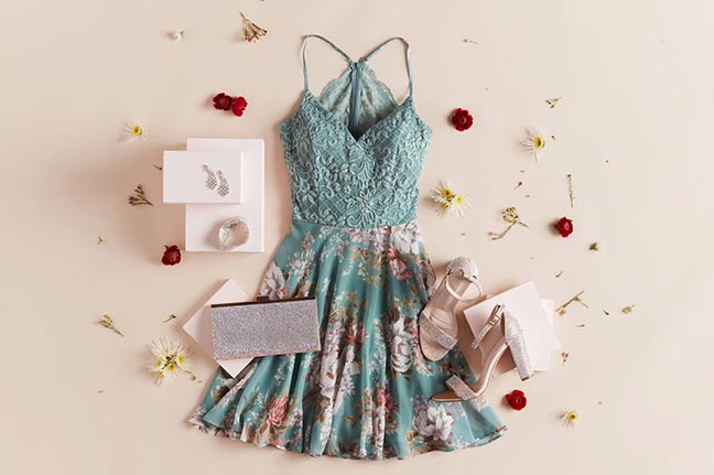teal floral patterned dress laid out next to shoes, clutch, earrings, and flowers