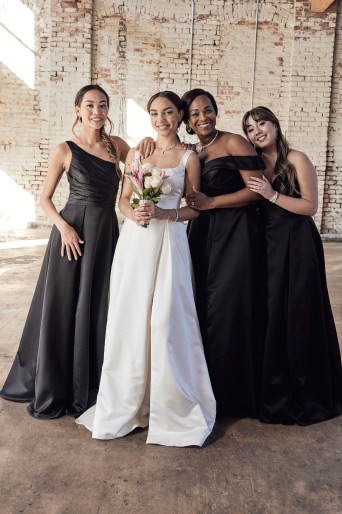 bride posing with her bridal party dressed in black