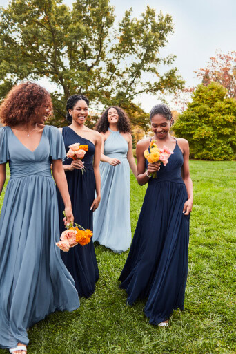3 bridesmaids in blue enchanted dresses walking with flowers