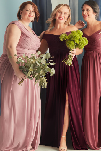 3 bridesmaids holding bouquets in front of blue curtains