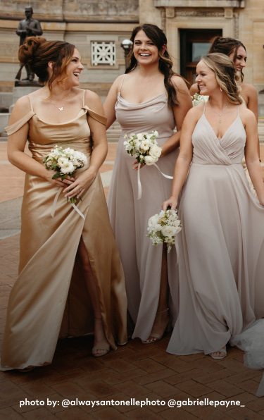 bride with all of her bridesmaids holding bouquets and walking outside