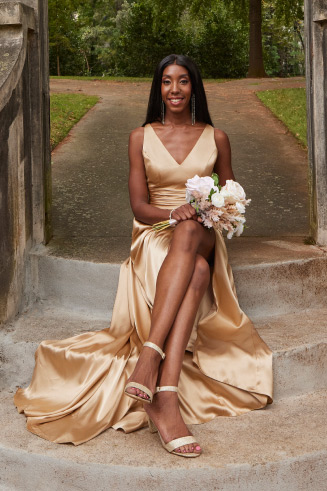 woman in bridesmaid dress sitting on steps holding flowers