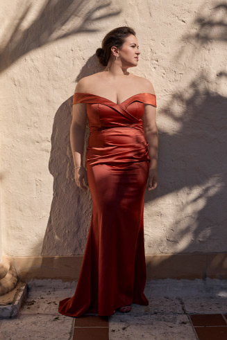 bridesmaid in red standing against a wall outside