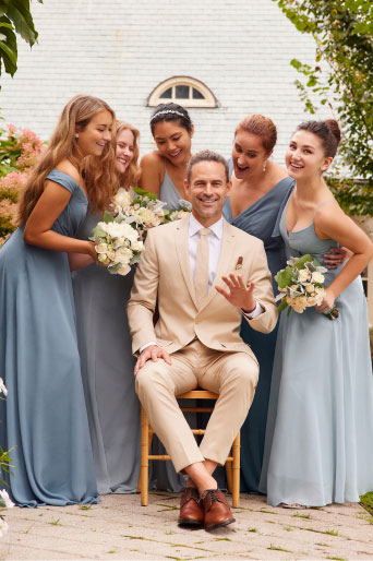 groom sitting outside surrounded by bridesmaids