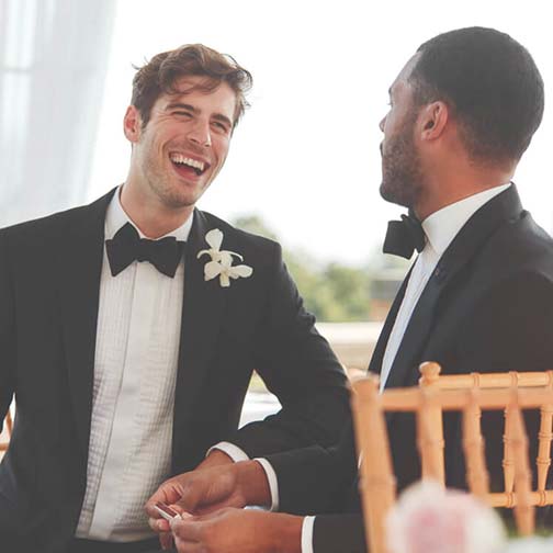 groom and groomsman sitting at a table and talking