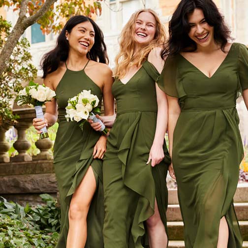 3 bridesmaids in green dresses walking and holding flower bouquets