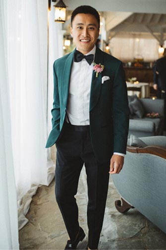 groom in a green tuxedo jacket and black pants wearing a bow tie