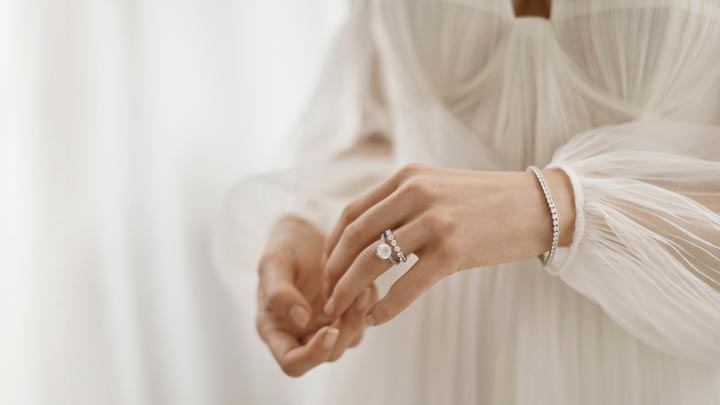 pair of hands wearing engagement and wedding rings and bracelet