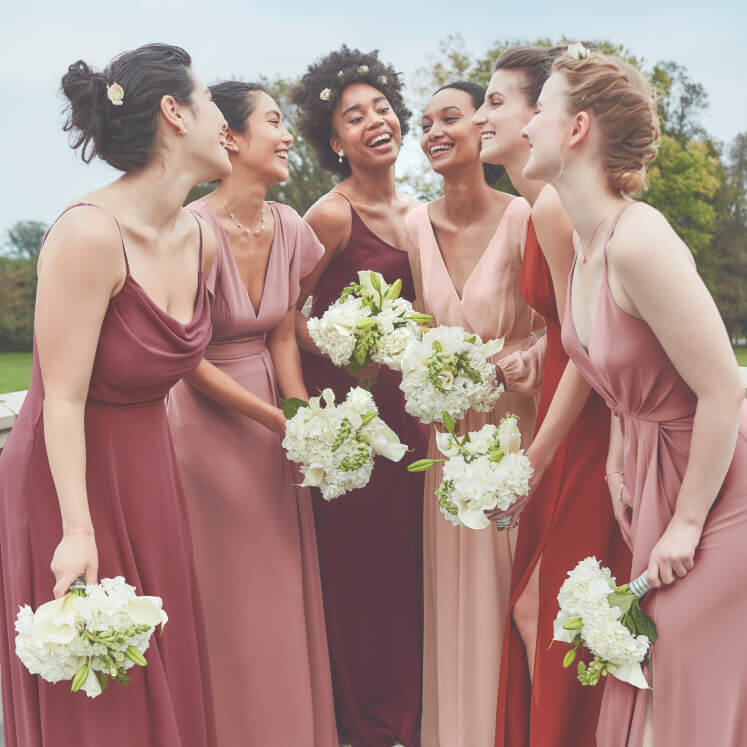 group of bridesmaids in different dresses standing together and holding flower bouquets