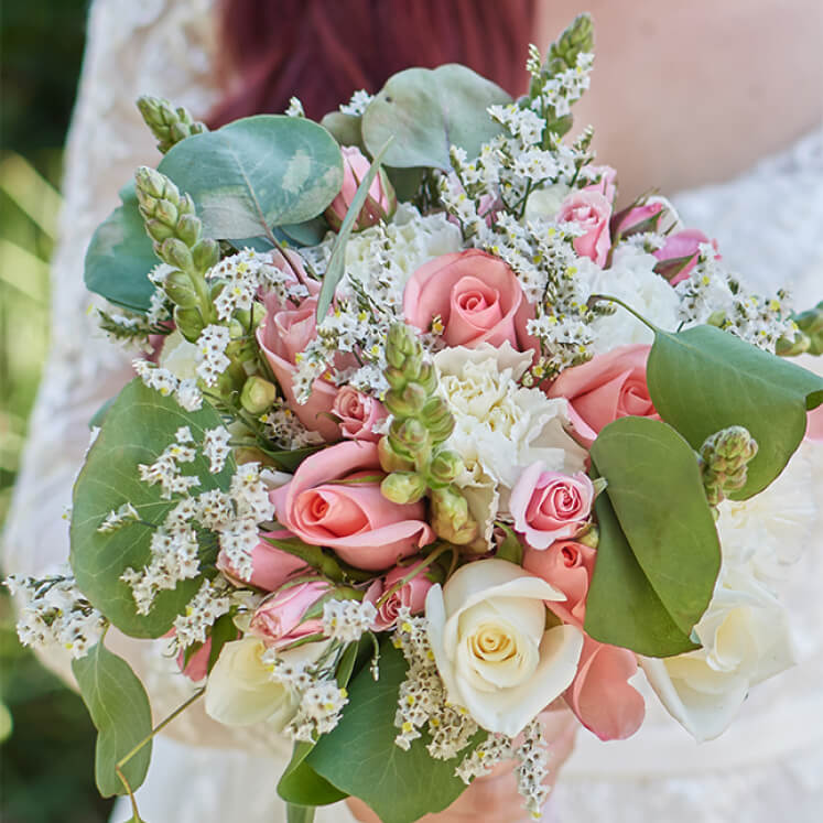 bride holding a bouquet of pink and white roses