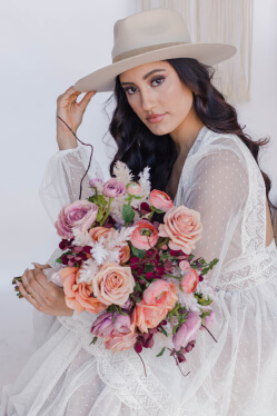 bride wearing a hat holding flower bouquet