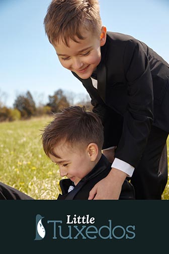 2 boys in little tux tuxedos playing in a field