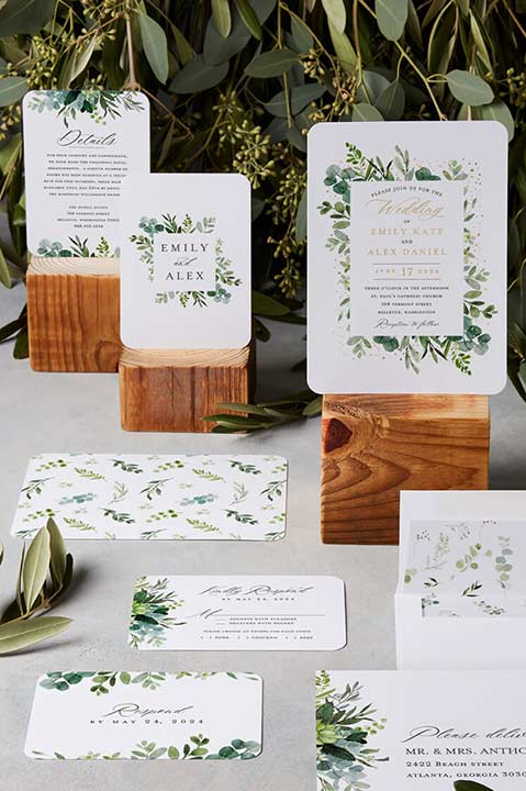 wedding invitation suite on wood blocks with branches on a table