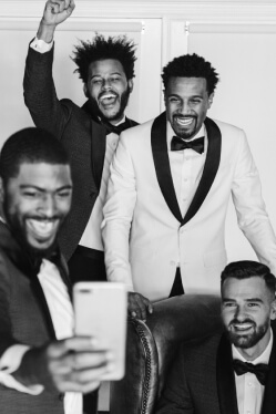 groom wearing a bow tie and tuxedo taking a selfie with groomsmen