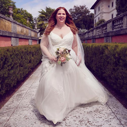 bride wearing a wedding dress and veil walking in courtyard