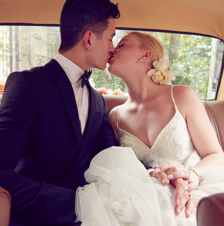 bride and groom kissing in back seat of car