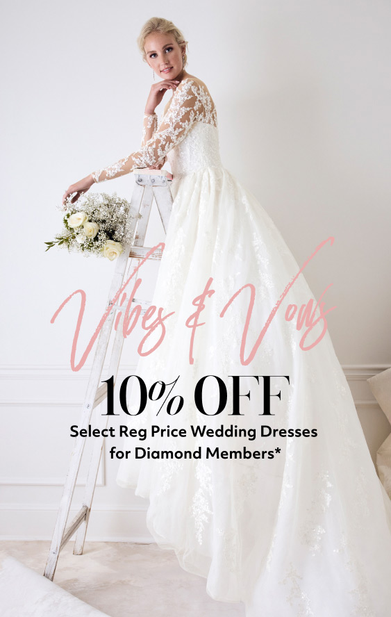 bride standing on a ladder promoting vibes & vows 10% off select reg price wedding dresses for diamond members*